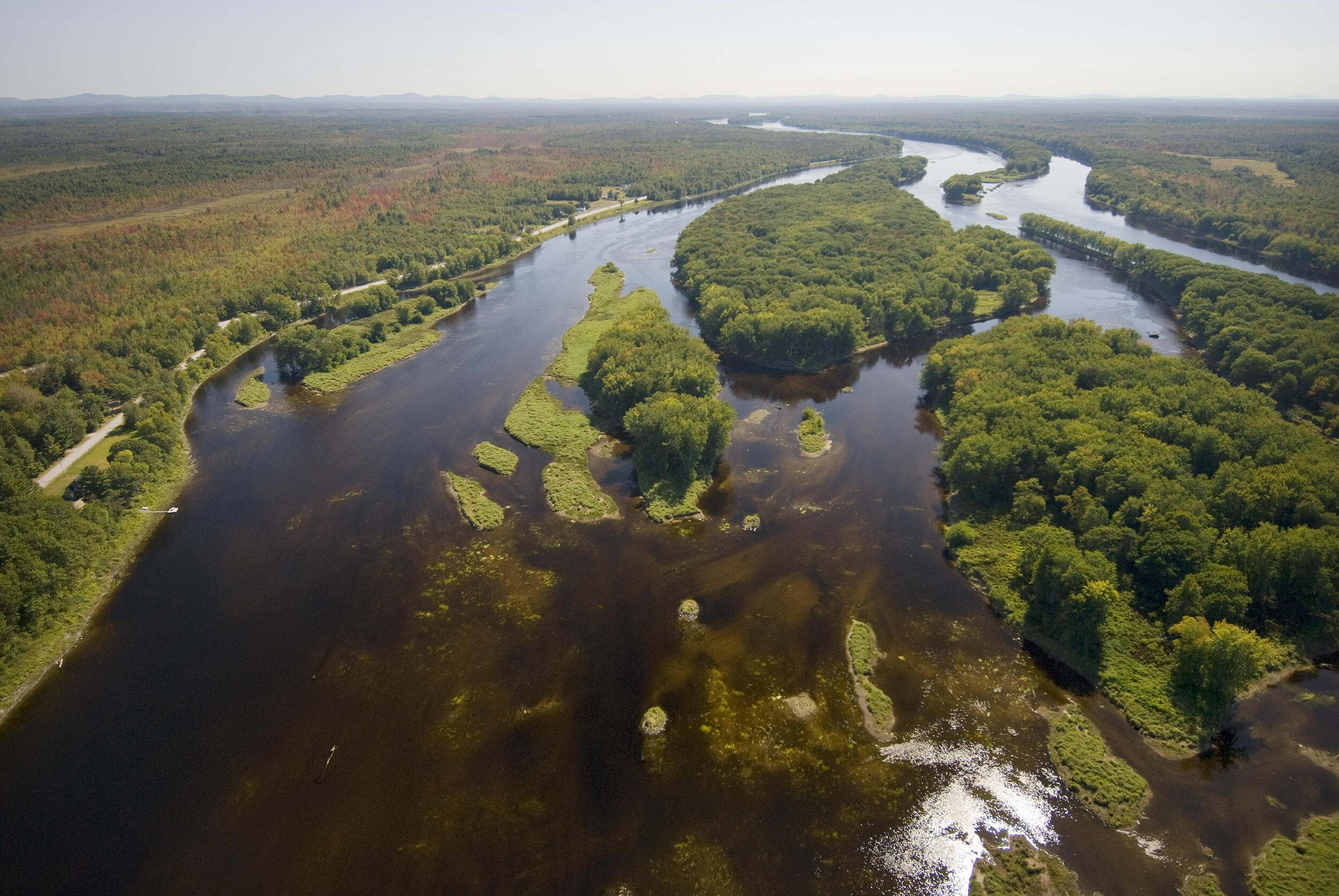 A wide river meanders around small islands in the middle of its channel.