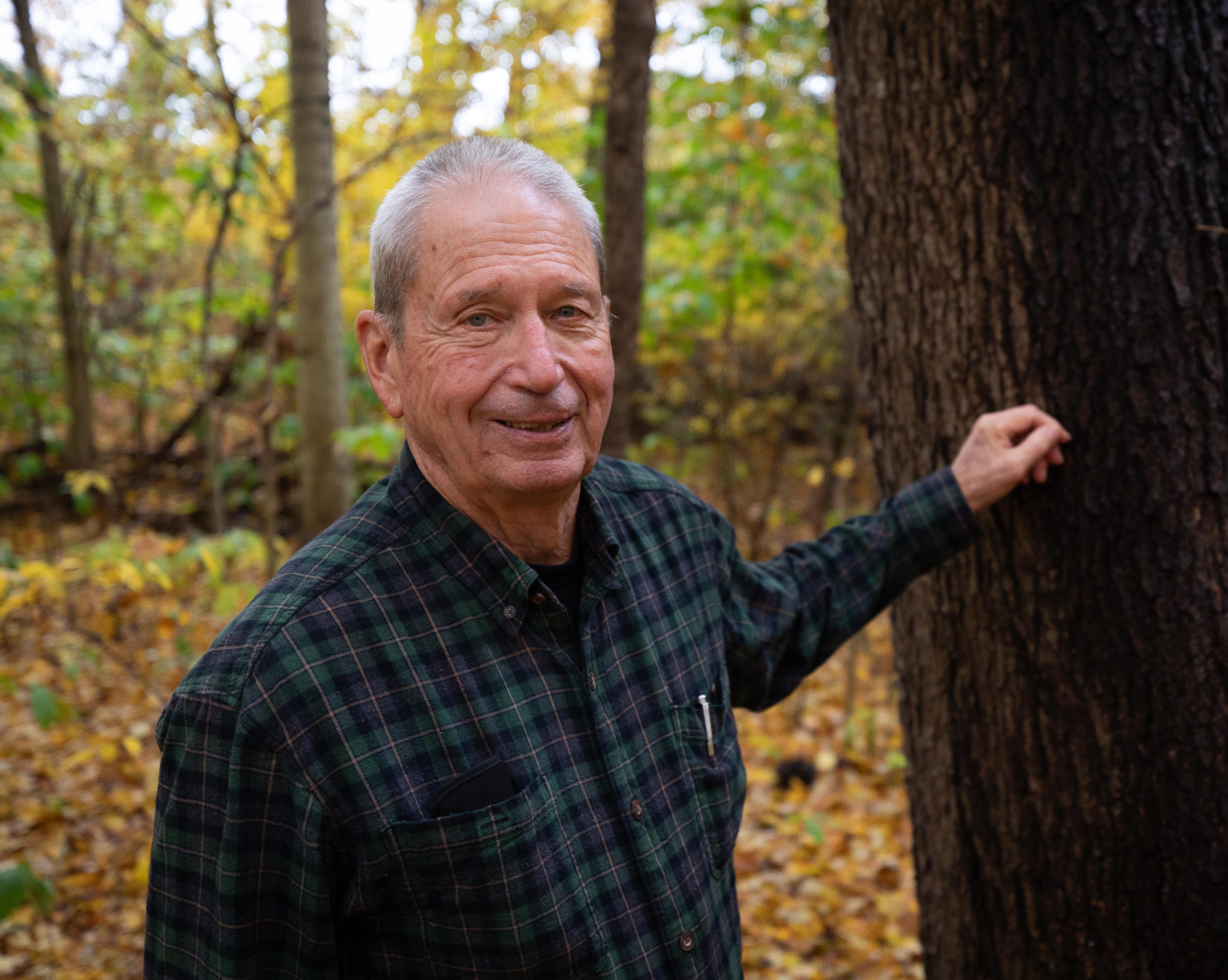 Landowner Charlie Hetrick stands next to a tree on his wooded property.
