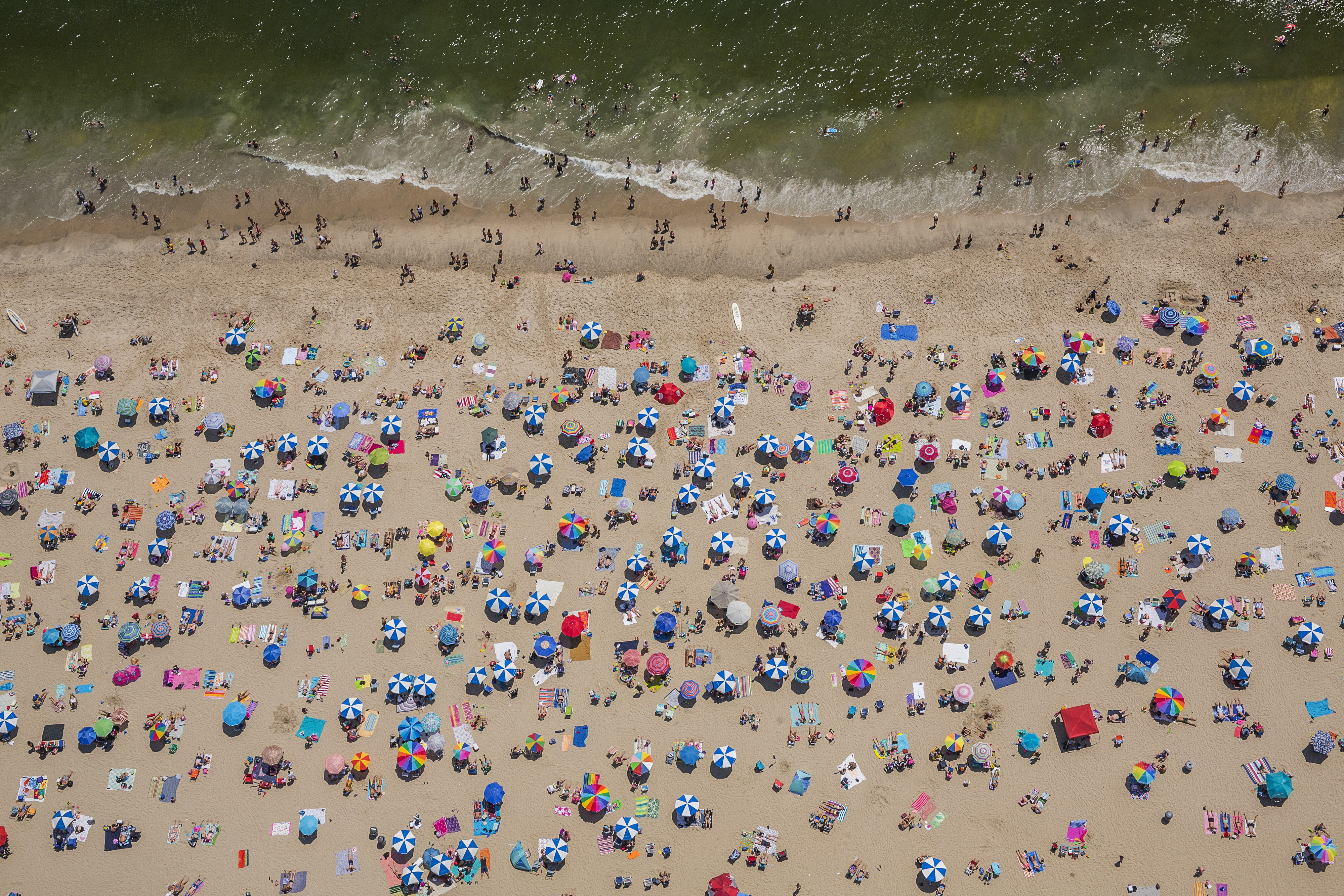 A view from the sky of beach with several people near the waterline.
