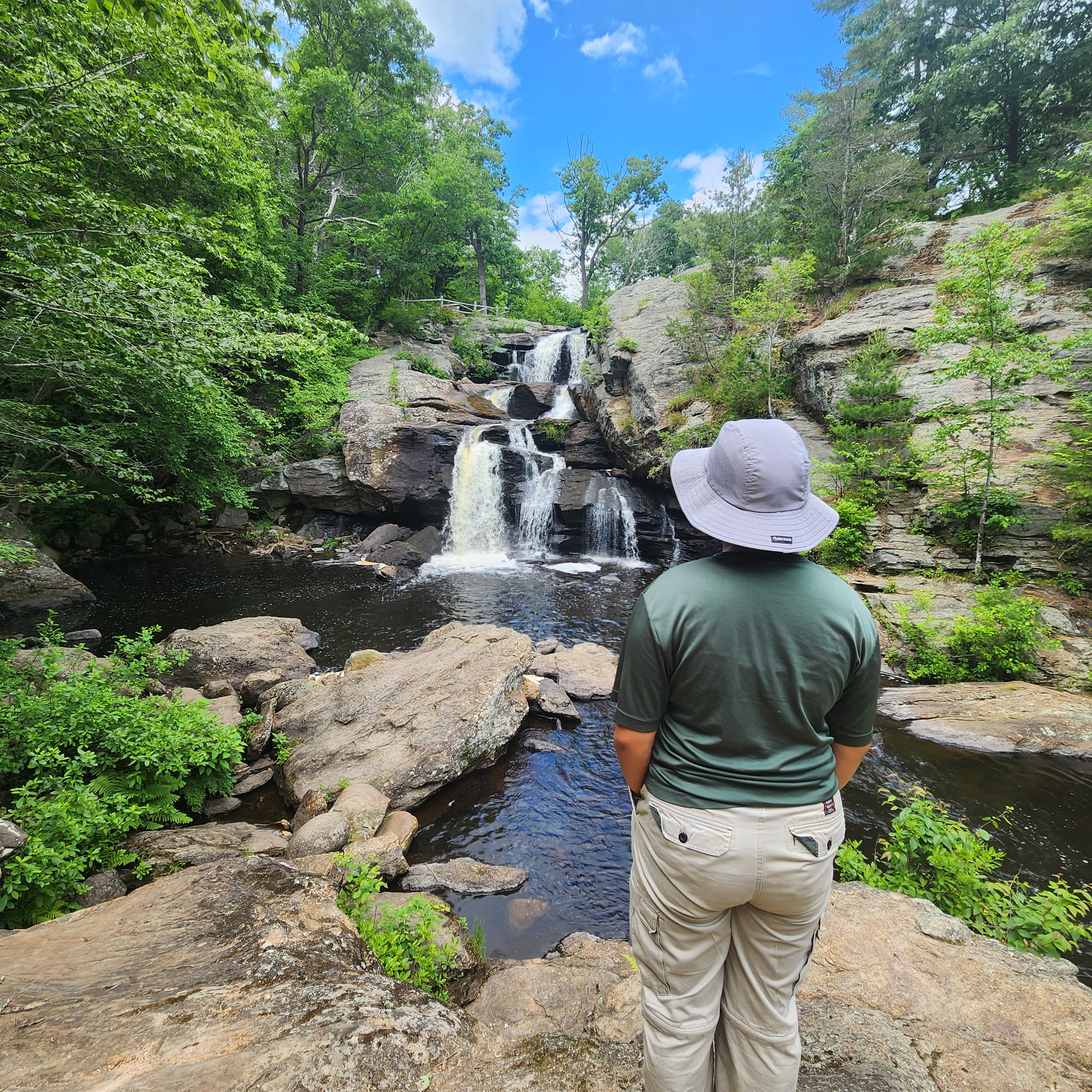 A person wearing a hat looks at a waterfall.