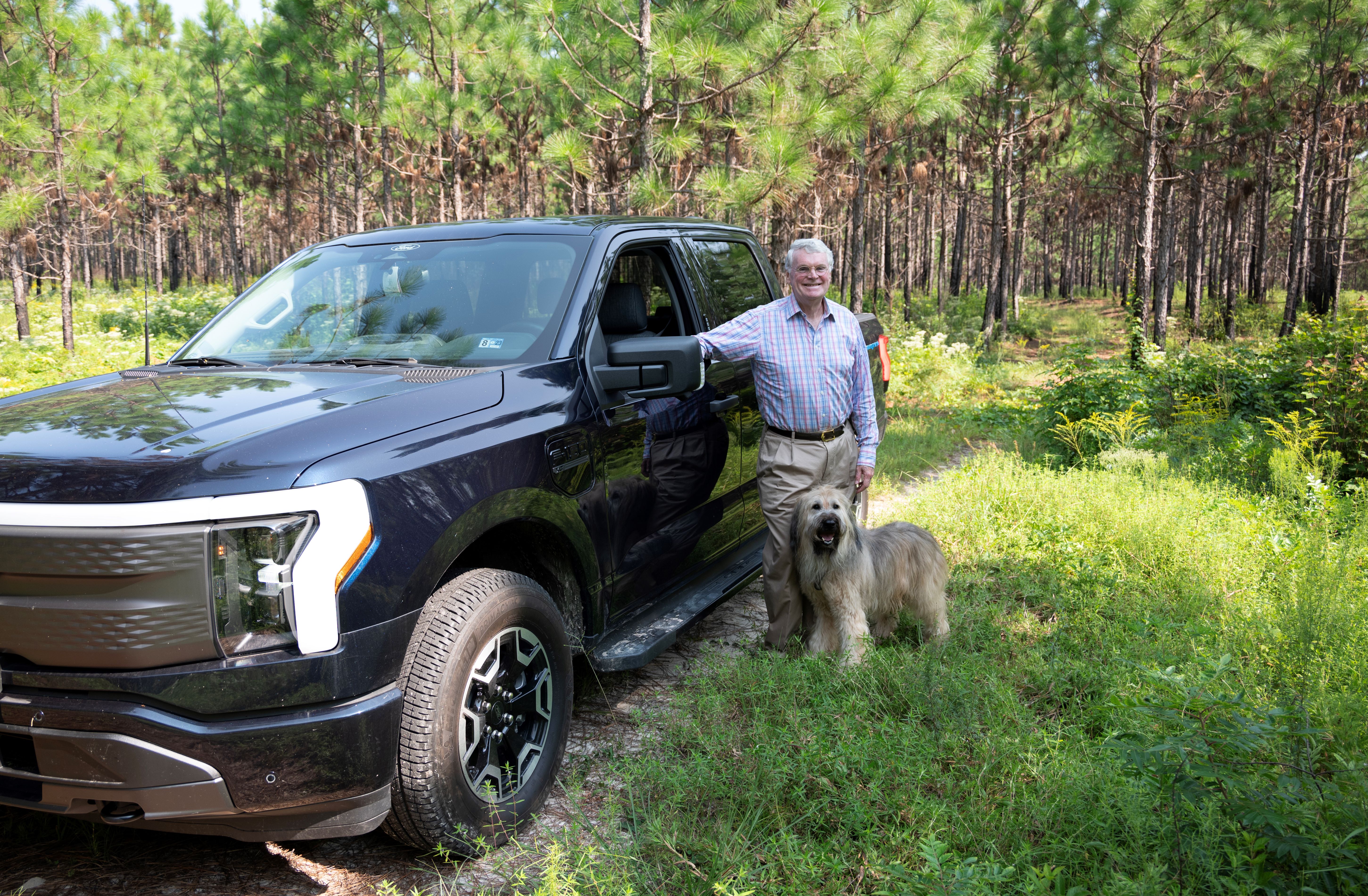 a man and dog posing for a picture next to a truck.