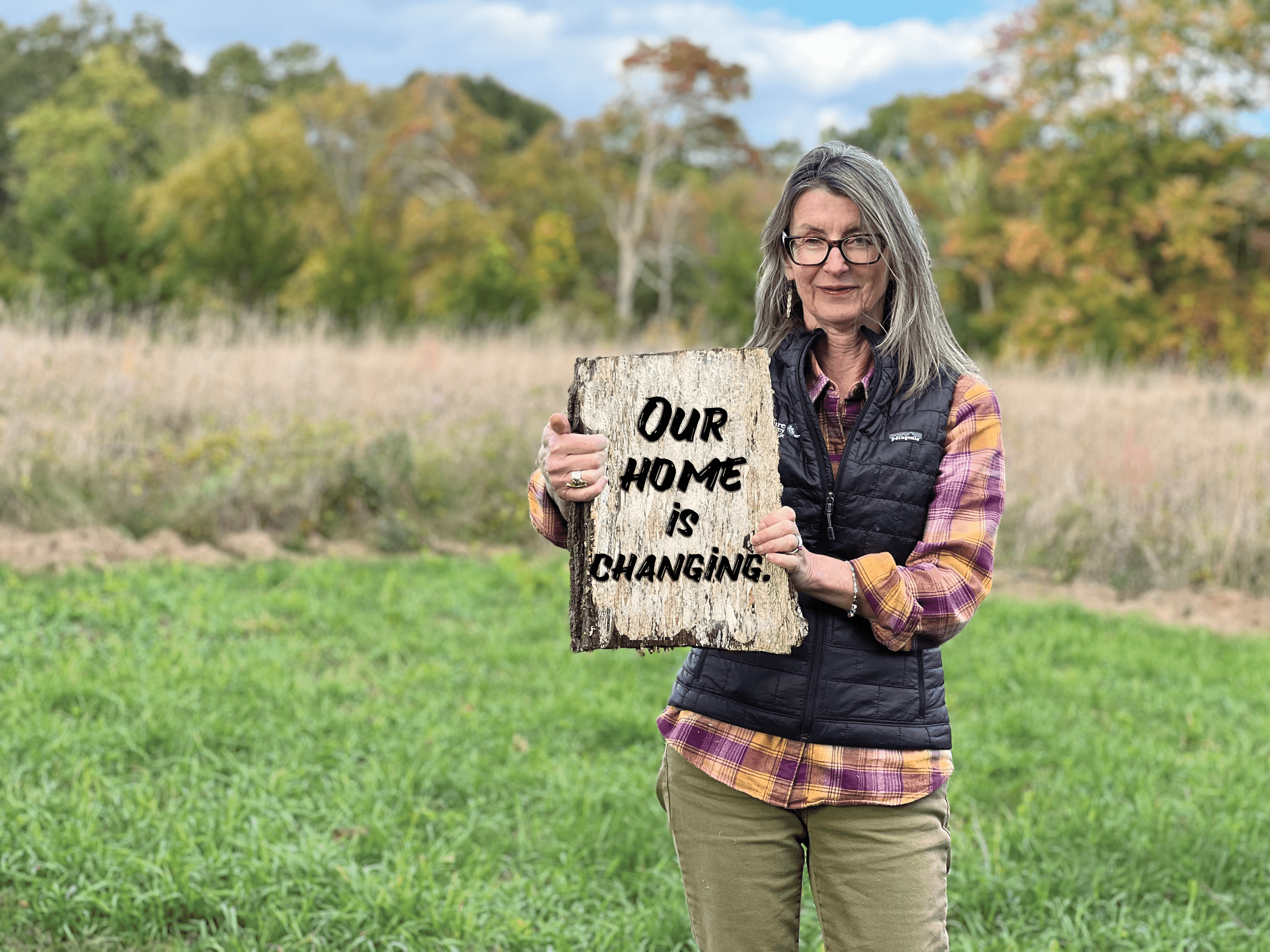 A woman holding a sign poses for a picture.