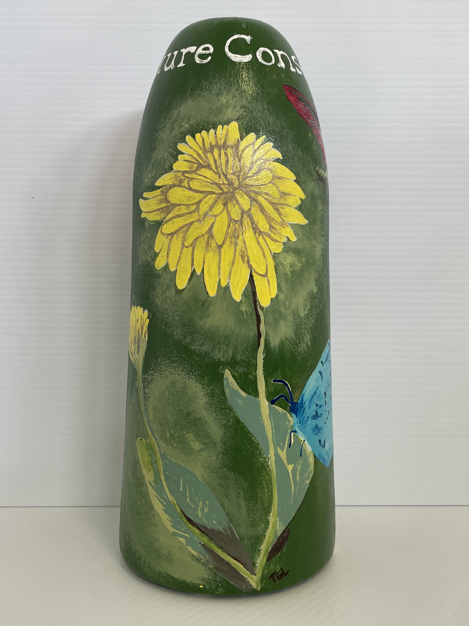 A lobster buoy is decorated with a yellow flower and other art.