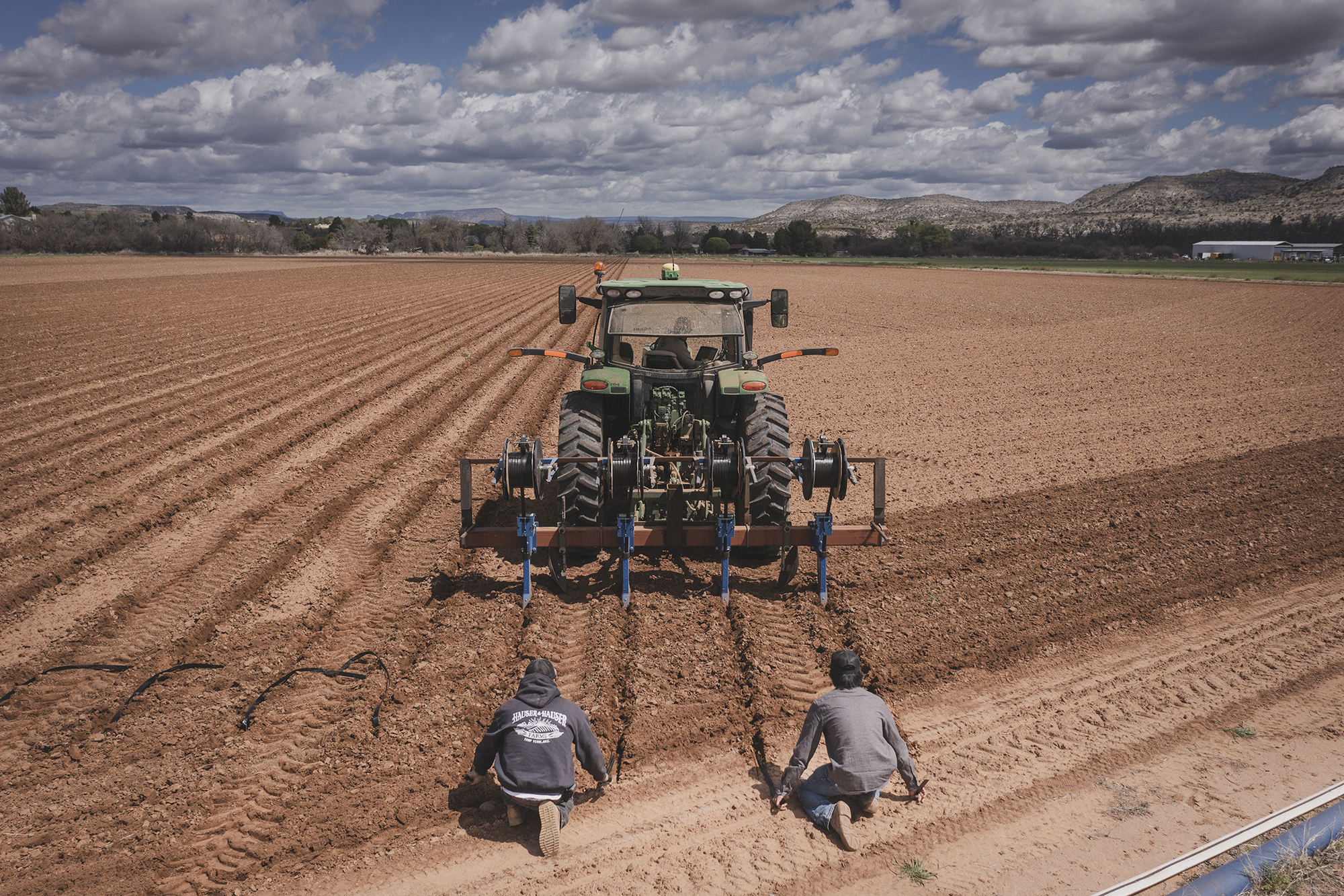 Two people attend to a tractor in an agricultural field