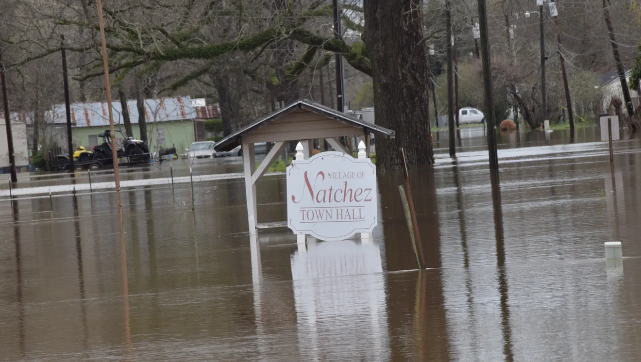 Water surrounds a town's sign.