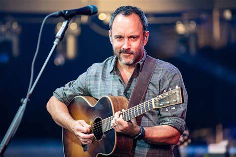 Dave Matthews performs onstage with his guitar.