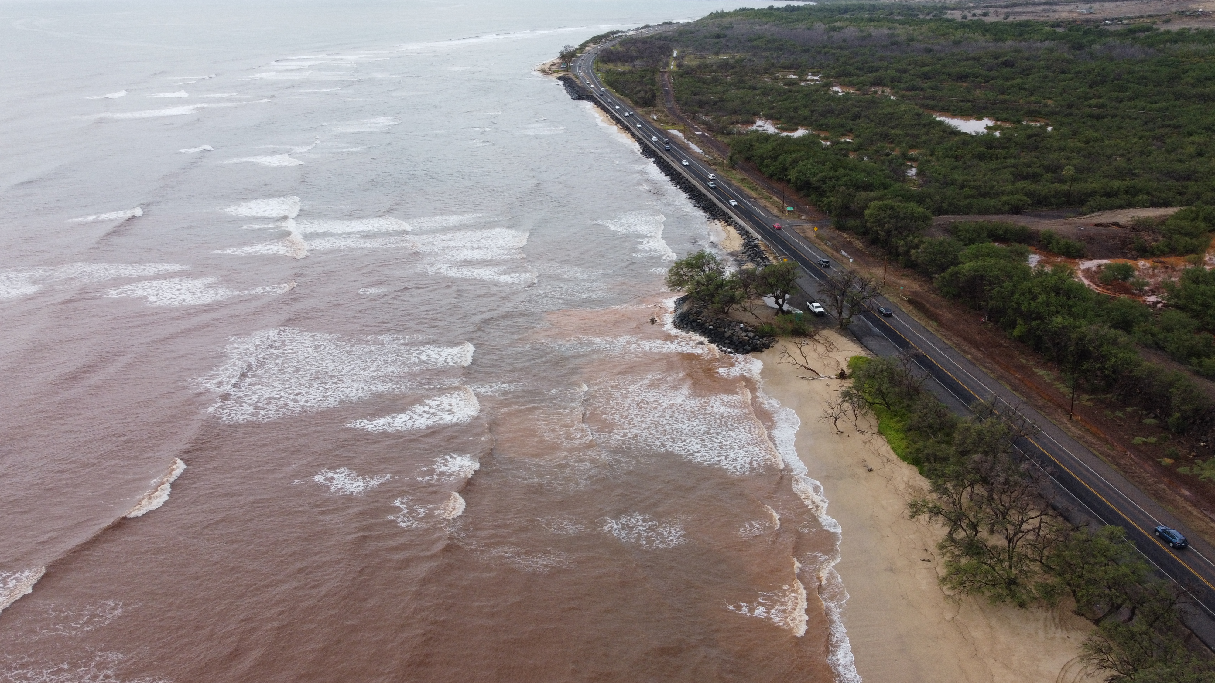 Brown sediment-filled ocean waters along a coast.