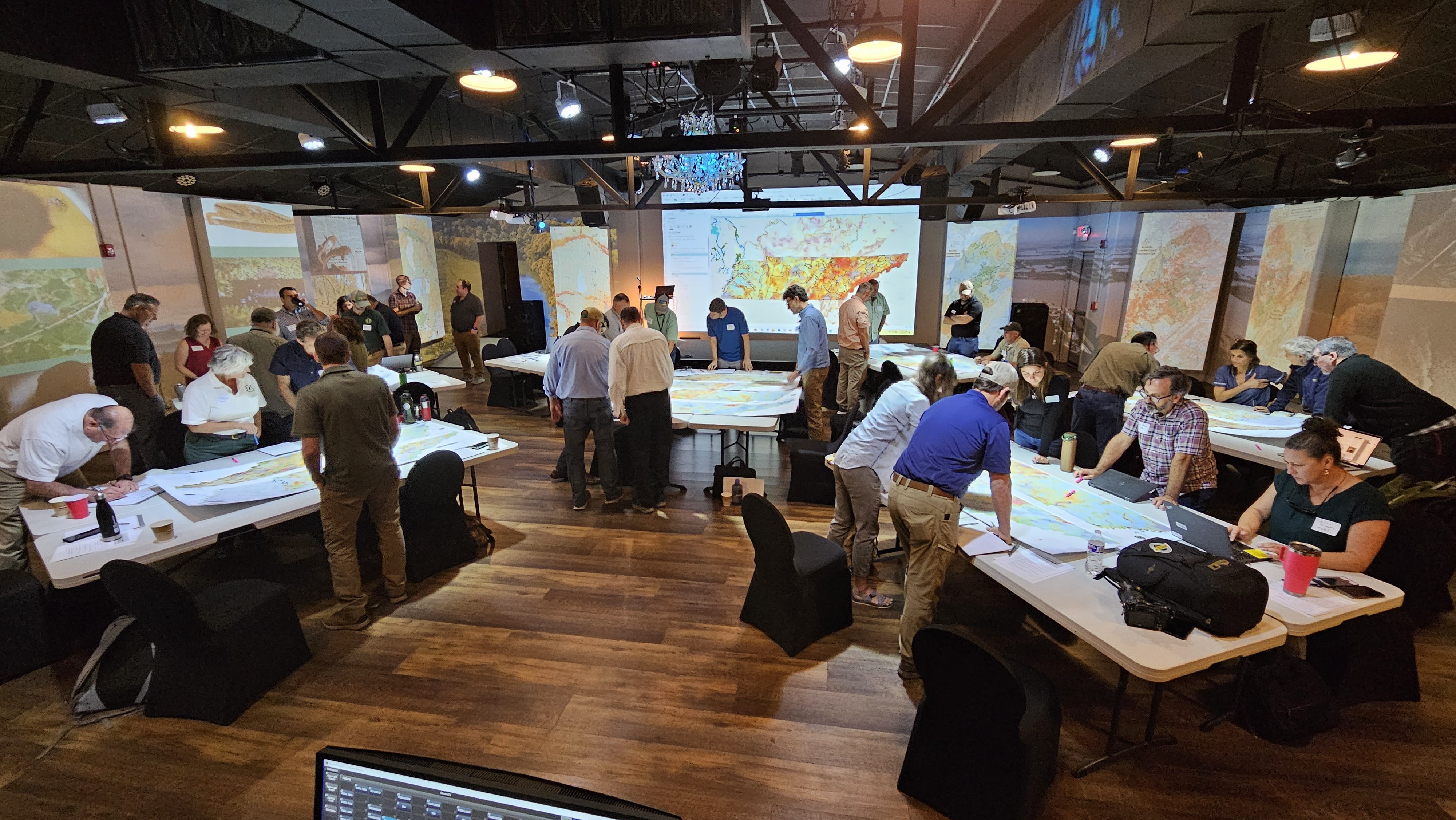 People gather to examine information presented on tables.