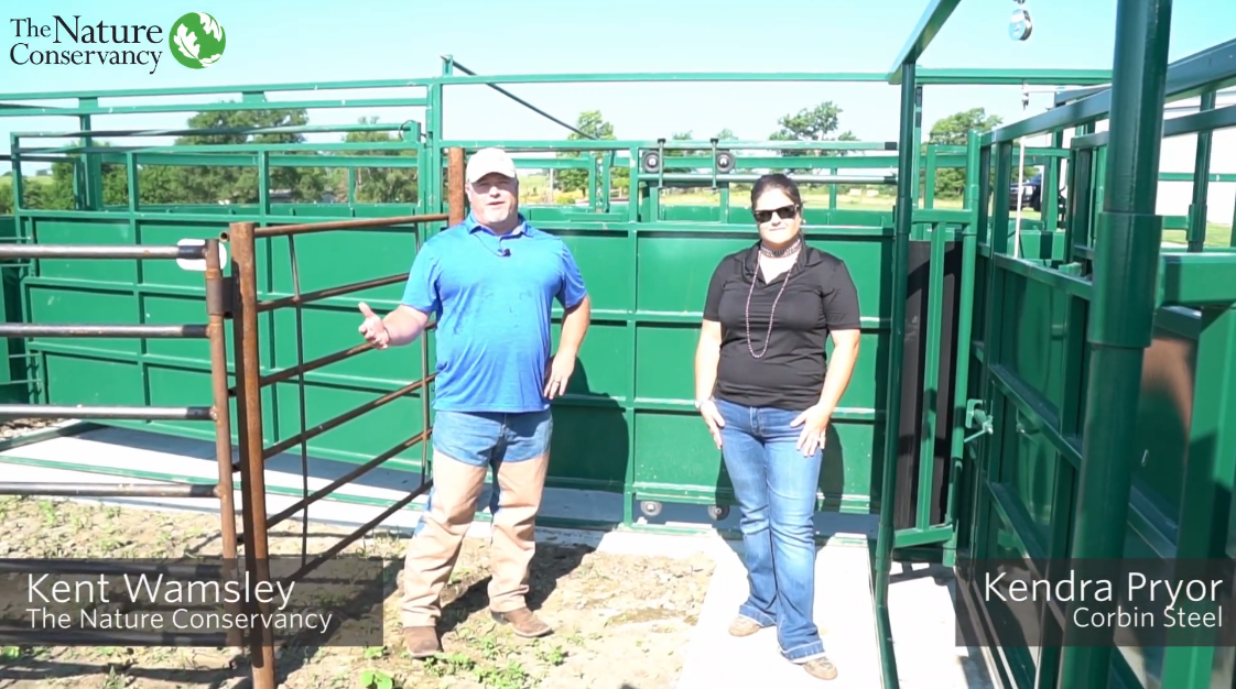 A man and a women standing in front of a metal corral.
