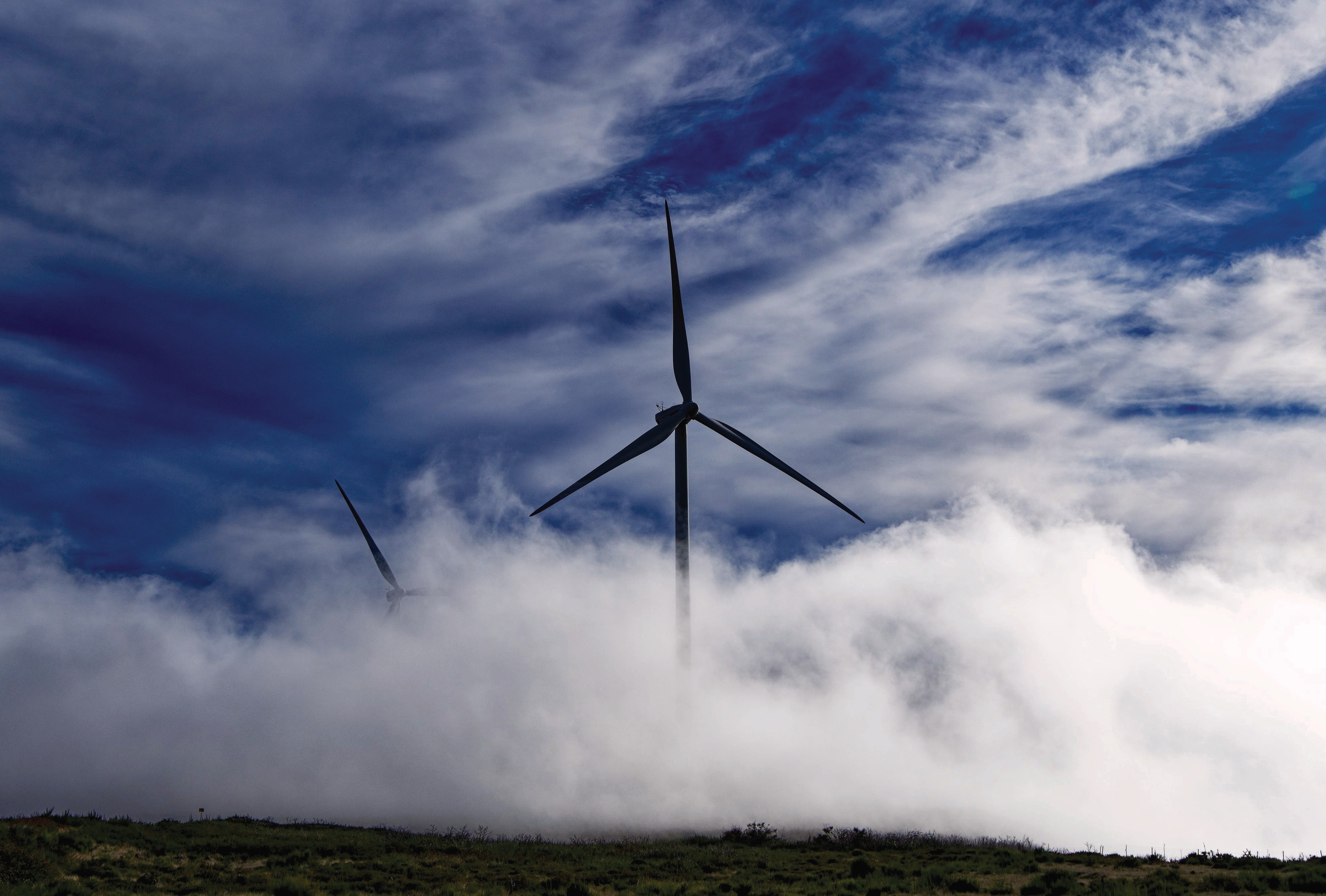 A wind turbine stands amid a foggy landscape.