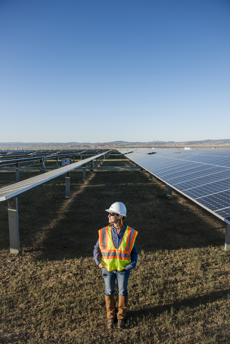 A woman stands in between rows of solar panels.