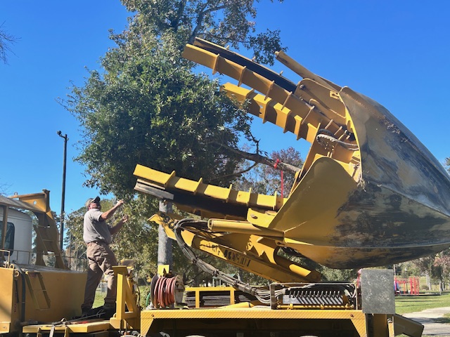 A man stands next to a large, yellow piece of equipment that resembles a giant claw.