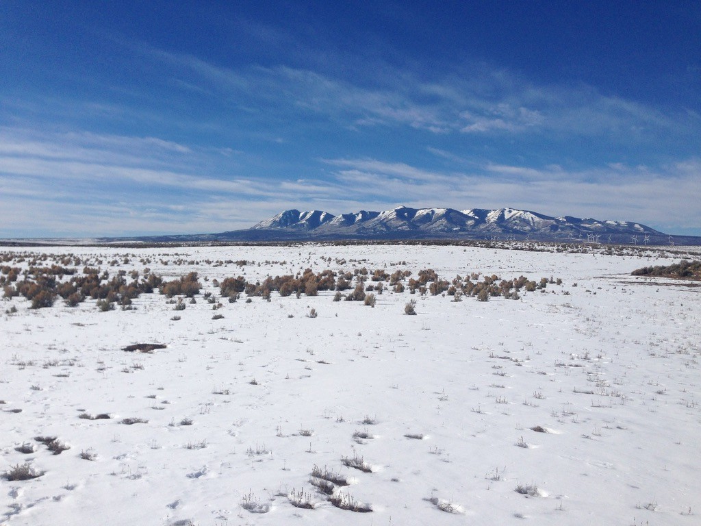 A landscape image of a snowy prairie and mountains in the background.