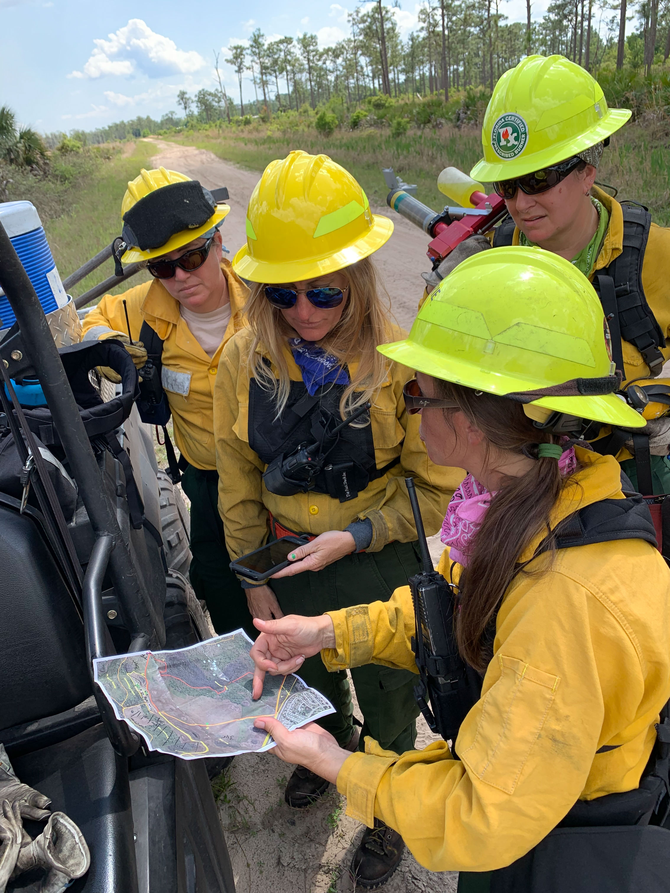 Four women wildland firefighters in the field looking at a map.